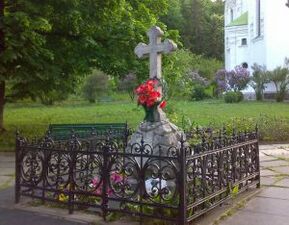 Надгробний пам’ятник із білого граніту у формі хреста на могилі К. Д. Ушинського. Під хрестом наведено епітафію. Київ, Видубицький монастир